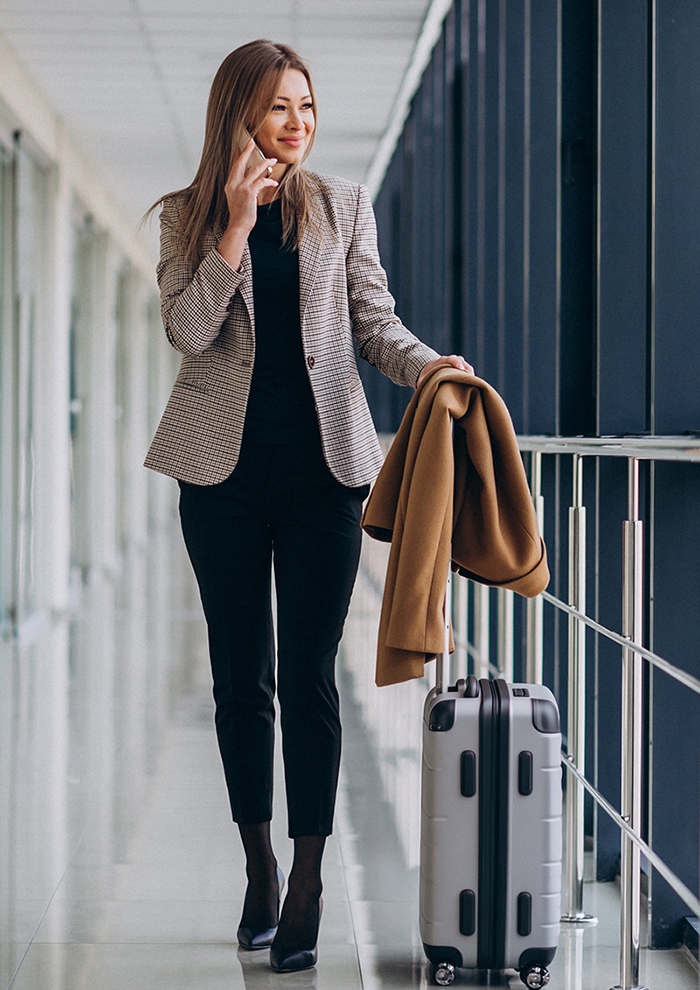 Business woman in terminal with travel bag talking on phone